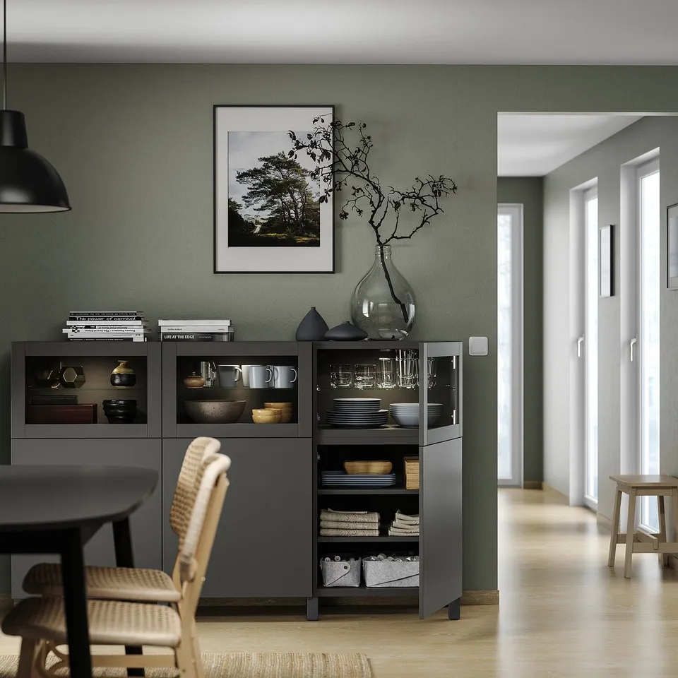 Modern dining room with besta storage, glass & wood decor, green walls.