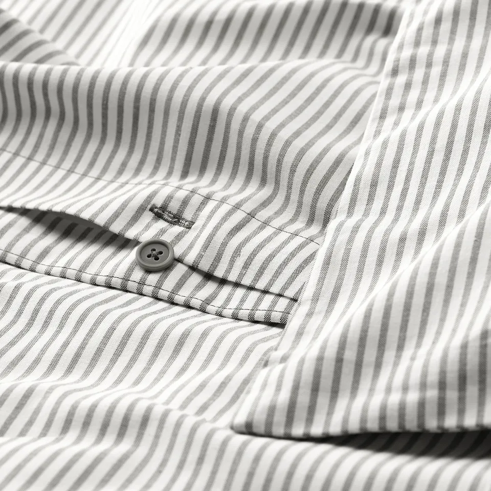 Close-up of grey and white striped fabric with a button, likely a shirt.