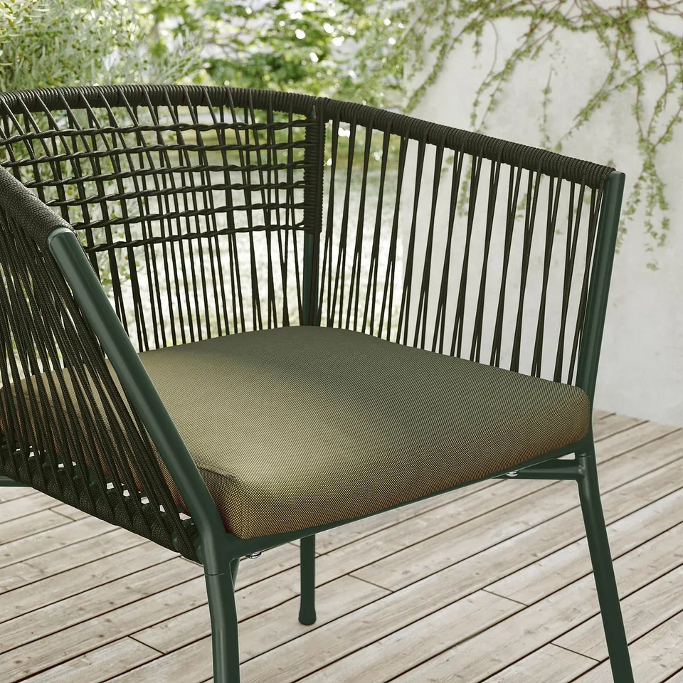 Black metal outdoor chair with woven seat and olive cushion.