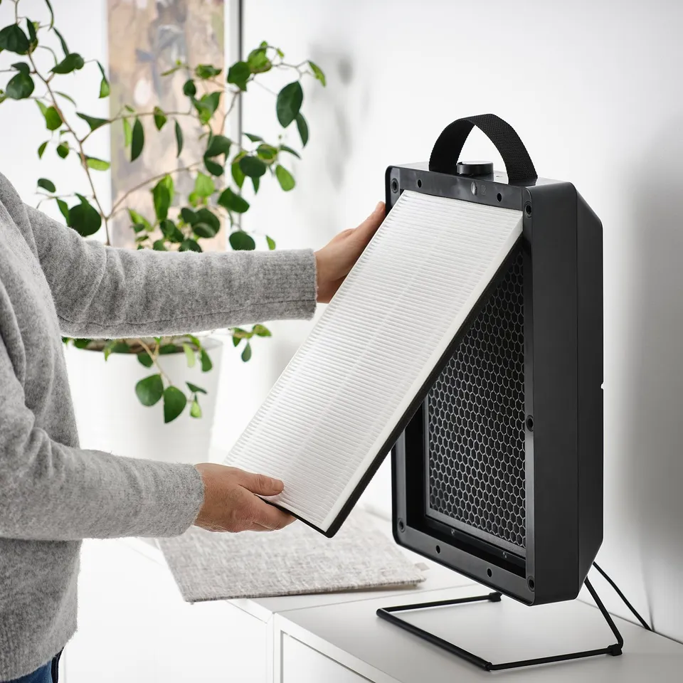 Person instals philtre into FÖRNUFTIG air purifier, improving indoor air quality.