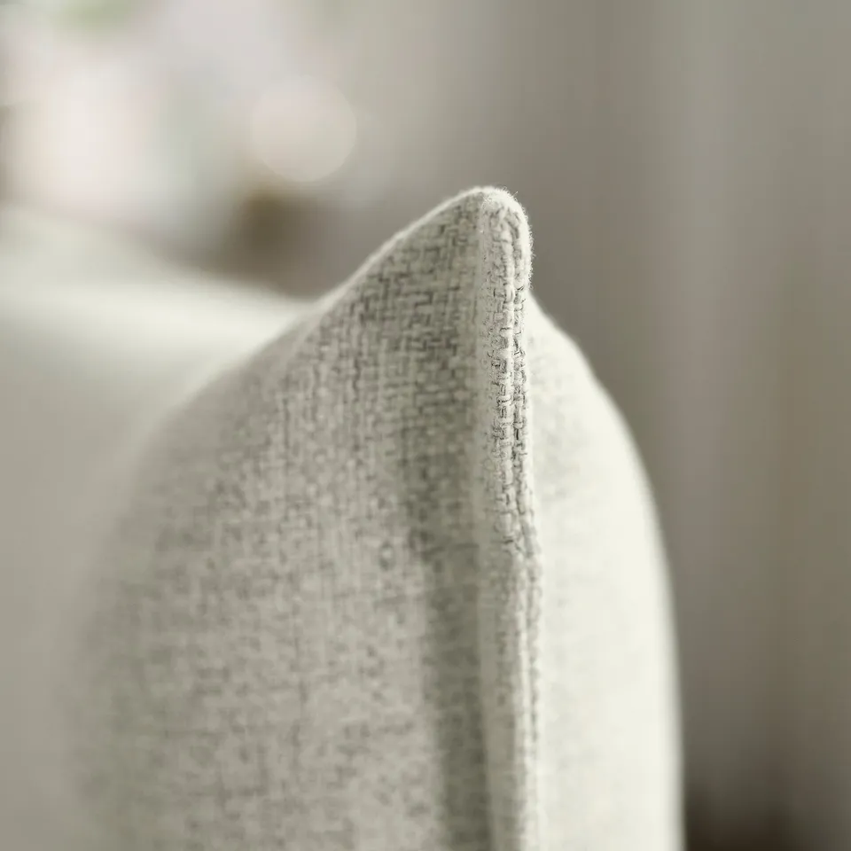 Close-up of soft, textured upholstery of modern sofa with visible stitching, highlighting comfort and quality.
