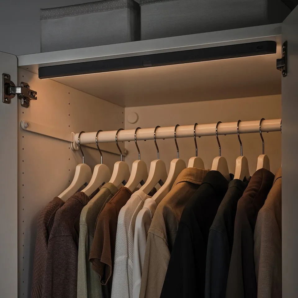 Closet with KÖLVATTEN light. Clothes on hangers, lit automatically by motion sensor.