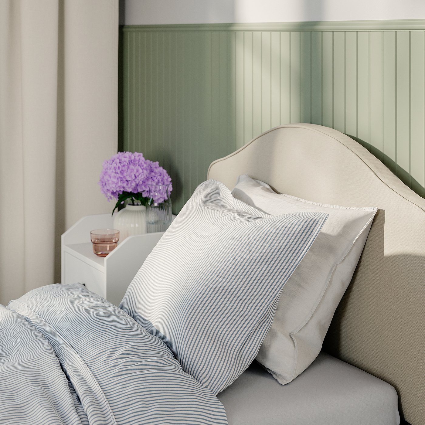 Bed with upholstered headboard, striped pillows, and bedside table with flowers.