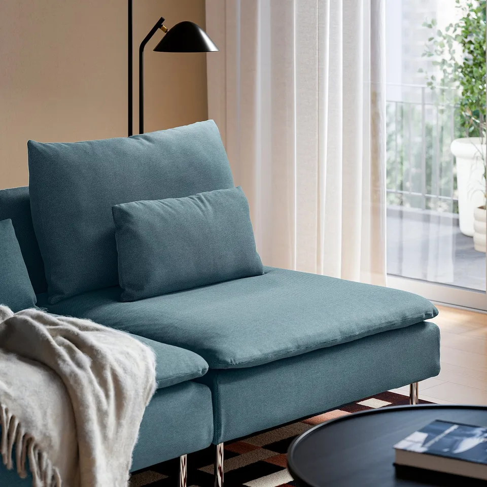 Light blue SÖDERHAMN sofa with cushions and blanket, near a window.