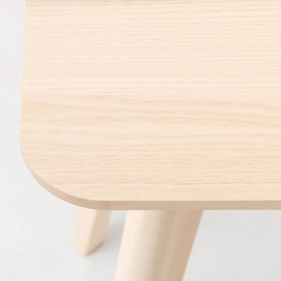 Close-up of a smooth, light-colored wooden table top with visible grain pattern.
