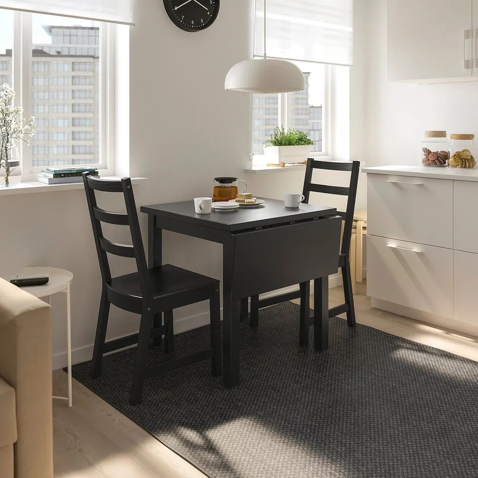 Black NORDVIKEN drop table with 2 chairs in small, bright kitchen.