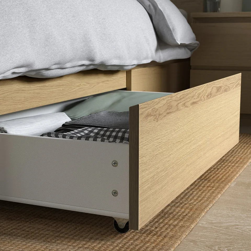 Open wooden bed drawer with folded fabrics, showing storage under bed.