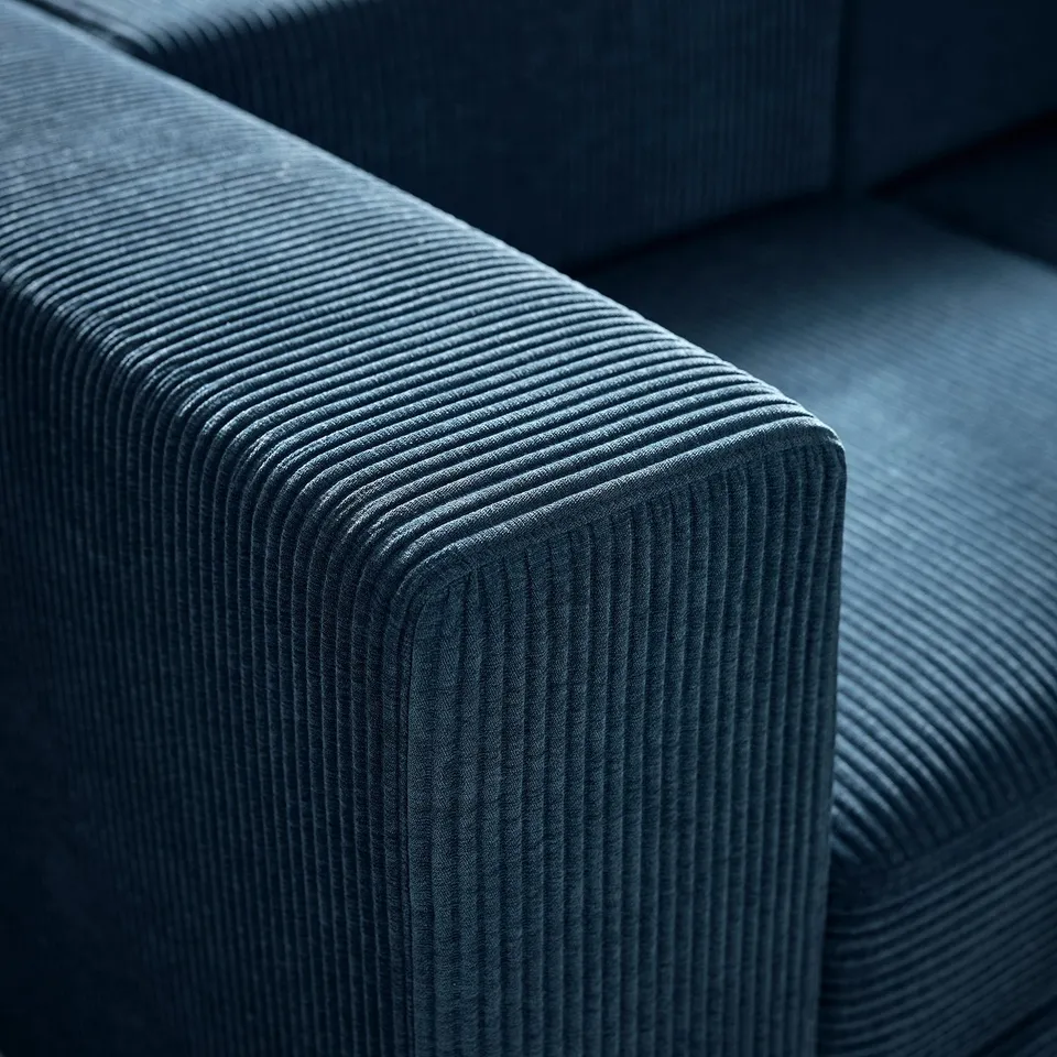 A close-up of a plush, deep-blue corduroy sofa, showcasing its soft, ribbed texture and inviting comfort.