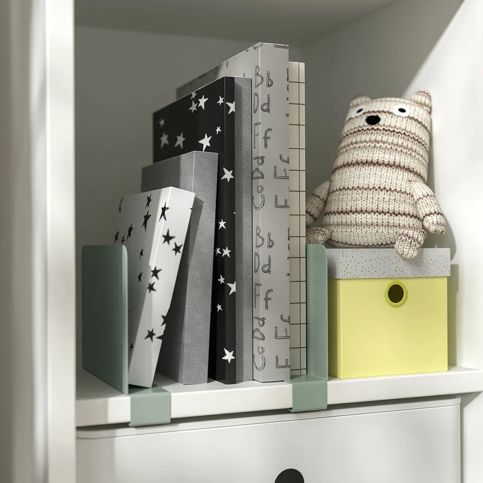 A shelf with patterned bookends, a stuffed bear, and a colourful box.