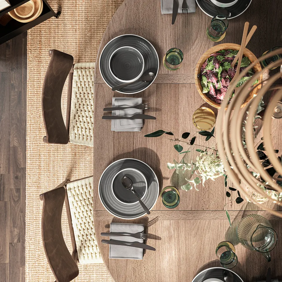 SKANSNÄS round dining table with leaf, beech wood, cosy setting with plates, cutlery, and food.