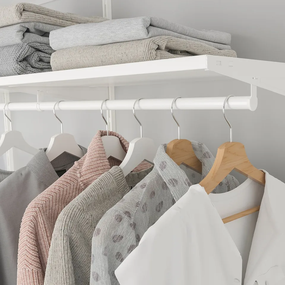 Closet with white BOAXEL rail; hangers and folded clothes organised.