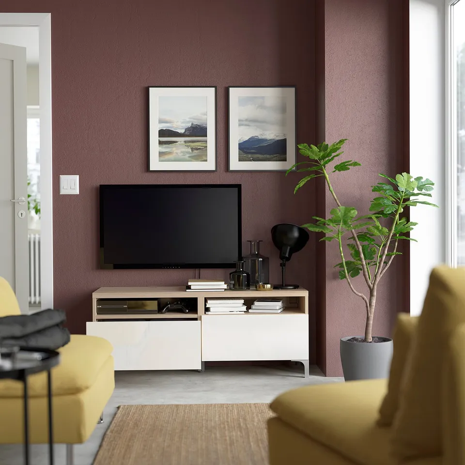 Modern living room with purple walls, BESTÅ tv stand, mounted tv, yellow armchairs, plant.
