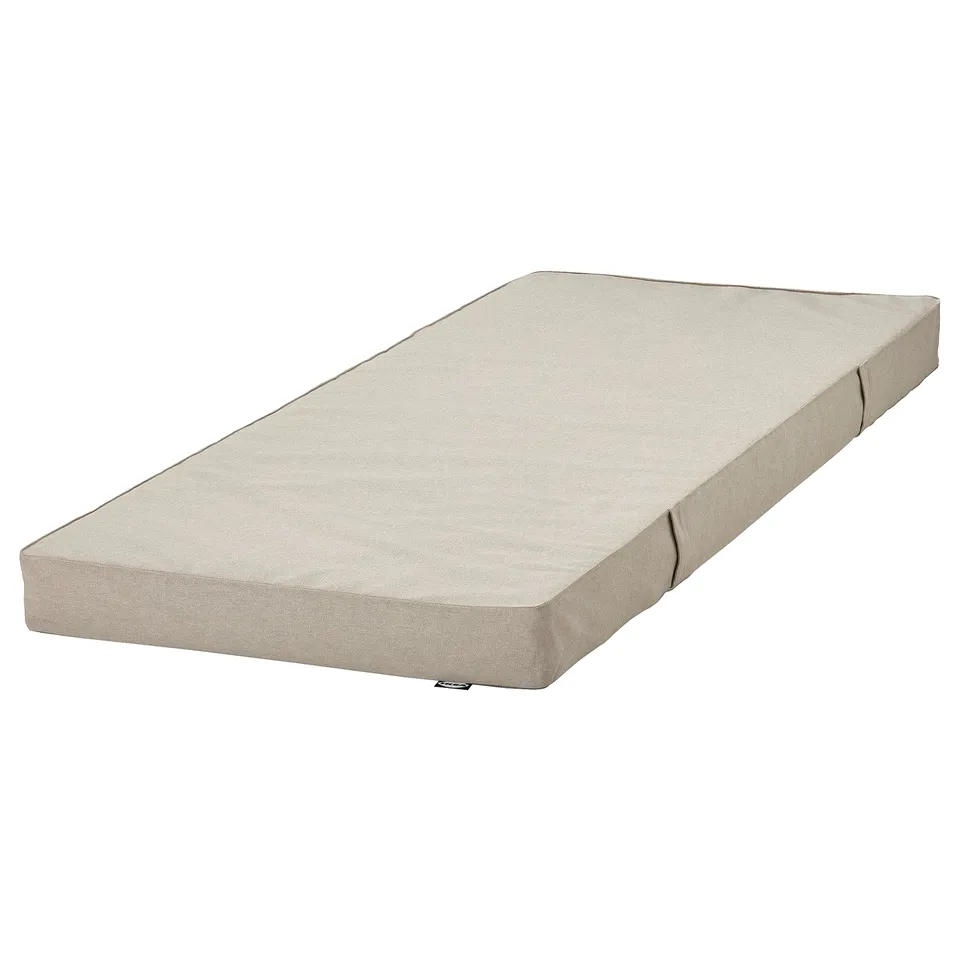 The VIHALS day-bed with a folded mattress. Its beige, rectangular, and has clean lines. Made from recycled materials.
