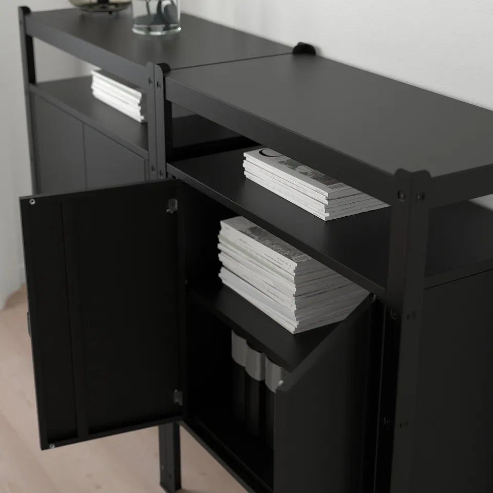 Black metal storage unit with three shelves holding stacked books. The shelves are sturdy and spacious, designed to hold heavy items.