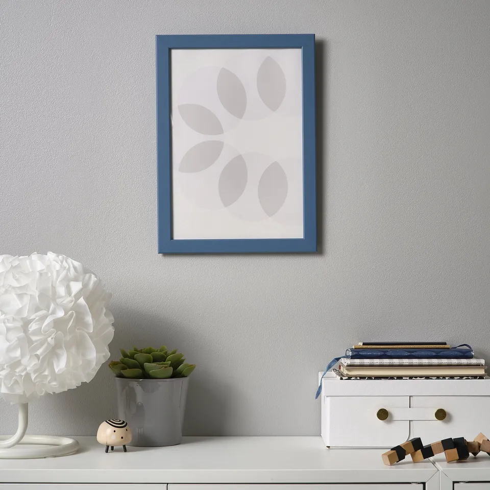A white shelf with blue picture, lamp, plant, figurine, books & blocks.