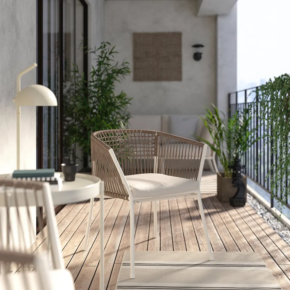 Modern balcony with beige SEGERÖN chair, white table, lamp, plants, and rug.