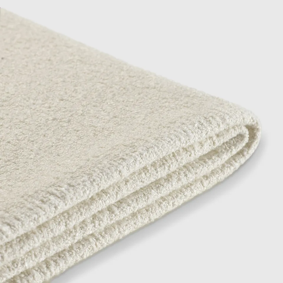 Folded white towel, textured soft fabric, clean and fresh appearance.