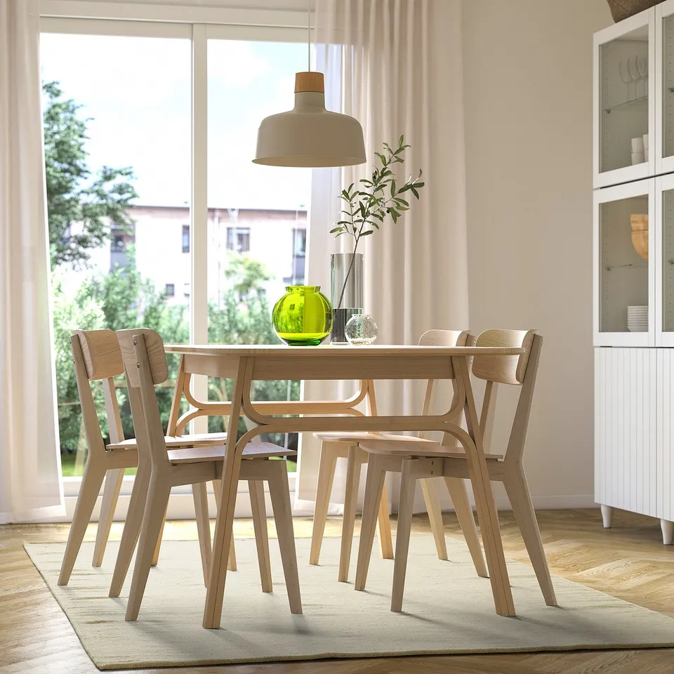 Modern dining set with light wood chairs, pendant lamp, large window, and rug.