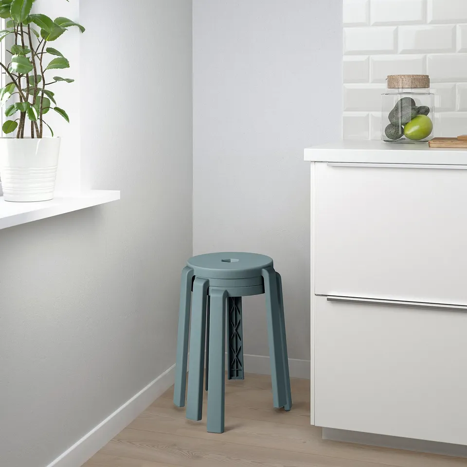 A teal stackable kitchen stool, versatile for seating or as a side table, practical and stylish, lightweight and durable.