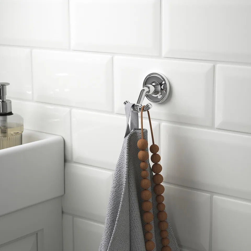Double towel hook with chrome finish hanging grey towel near sink.