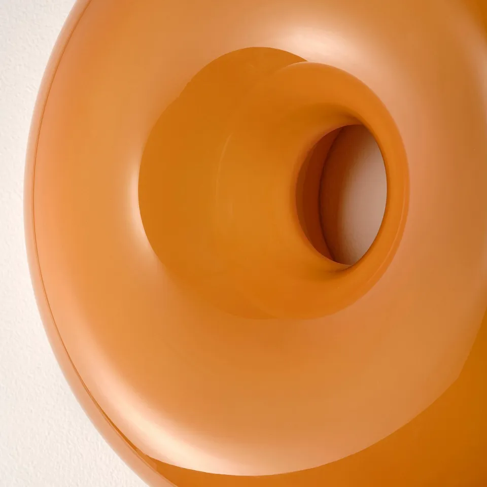 Orange glass lamp, smooth, soft glow, unique donut shape.