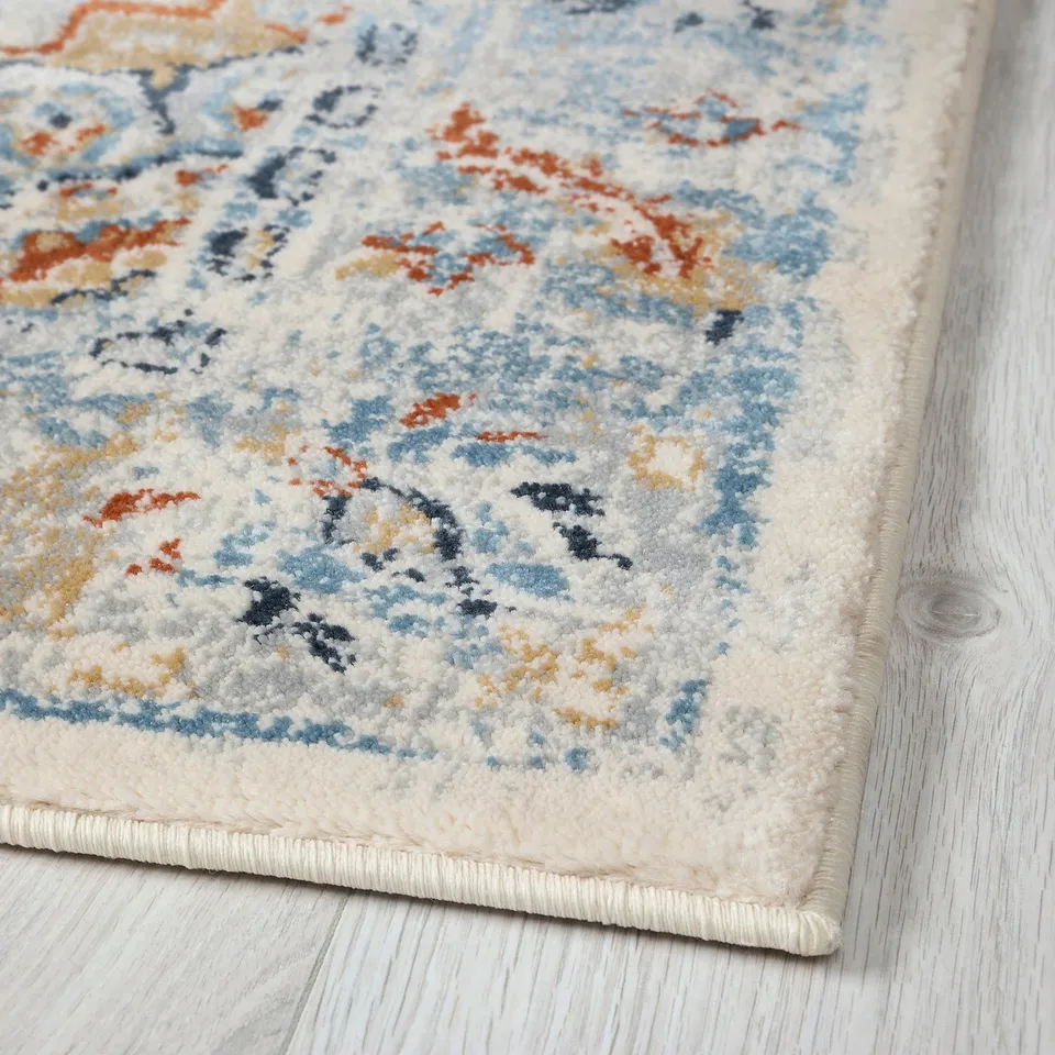 ONSEVIG area rug with intricate blue and orange patterns on a white background laying on wooden floor.