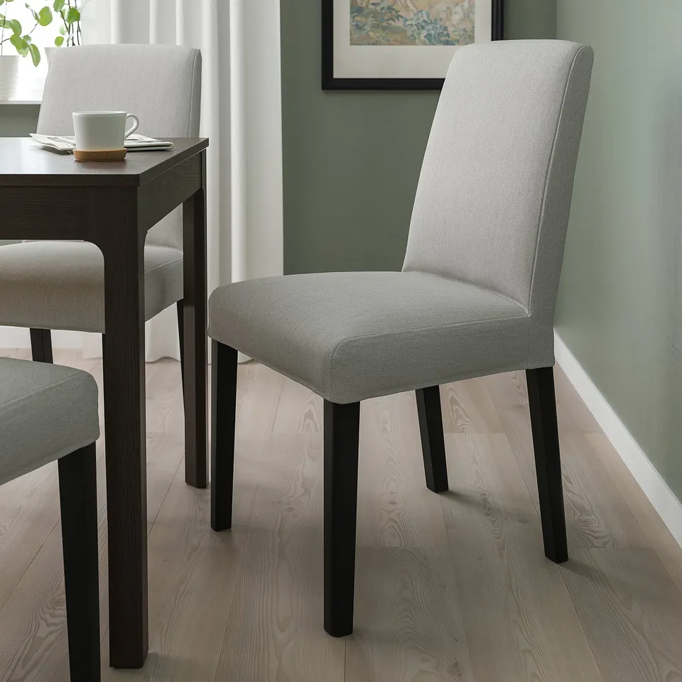 Modern grey upholstered dining chair with black legs, taller than table, cosy and stylish.