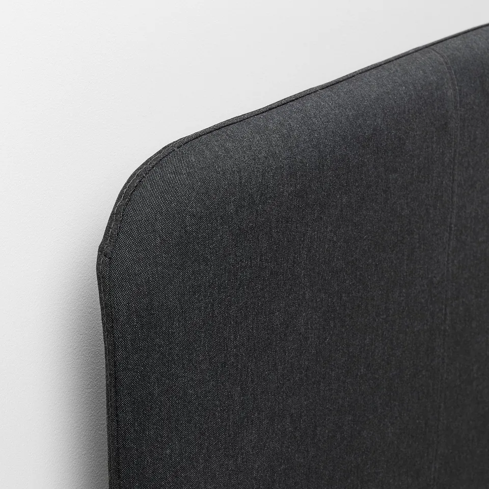 Close-up of black upholstered headboard, showcasing quality fabric and stitching.