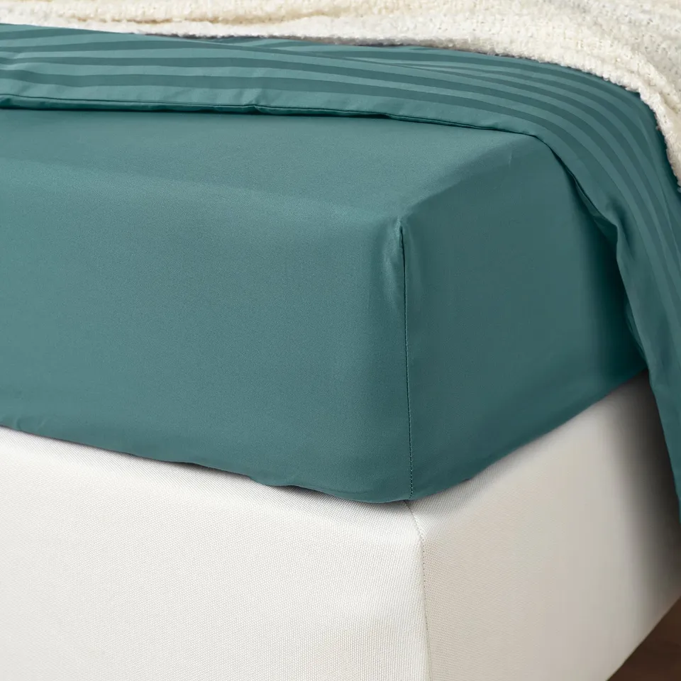 Bed sheet with blue-green sateen weave, pleated edge detail, and hemmed sides, showcasing thread count of 310.