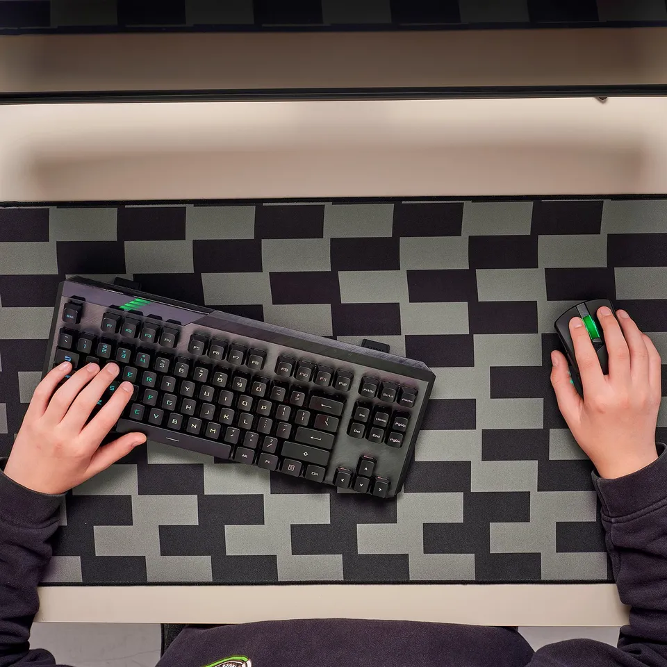 Person using keyboard and mouse on wide grey mouse pad. Ideal for gaming with smooth surface and firm grip.