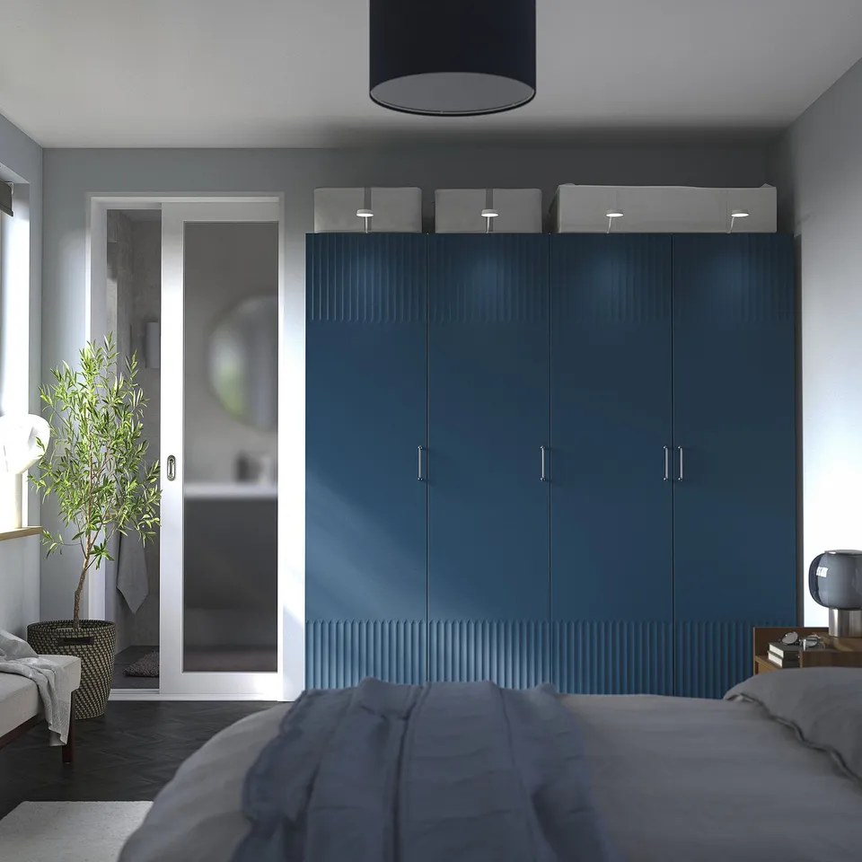 Modern bedroom with tall blue PAX wardrobe, grey bed, and glass bathroom door.