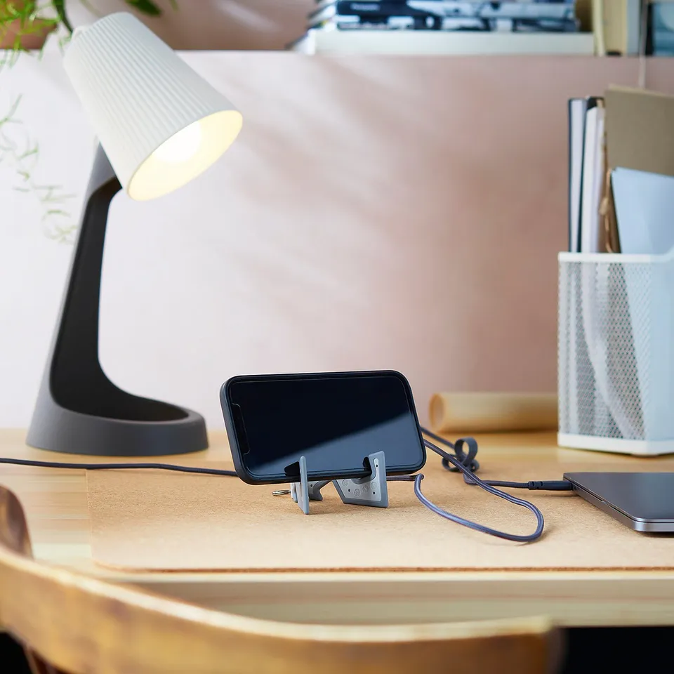 Desk with lamp, phone holder named YUPPIENALLE, and small accessories.