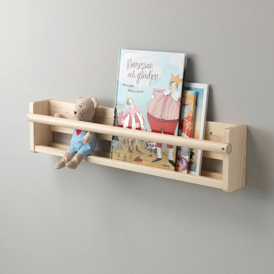 Wall-mounted wooden book shelf with bear cuddly toy. Holds childrens books for easy access.