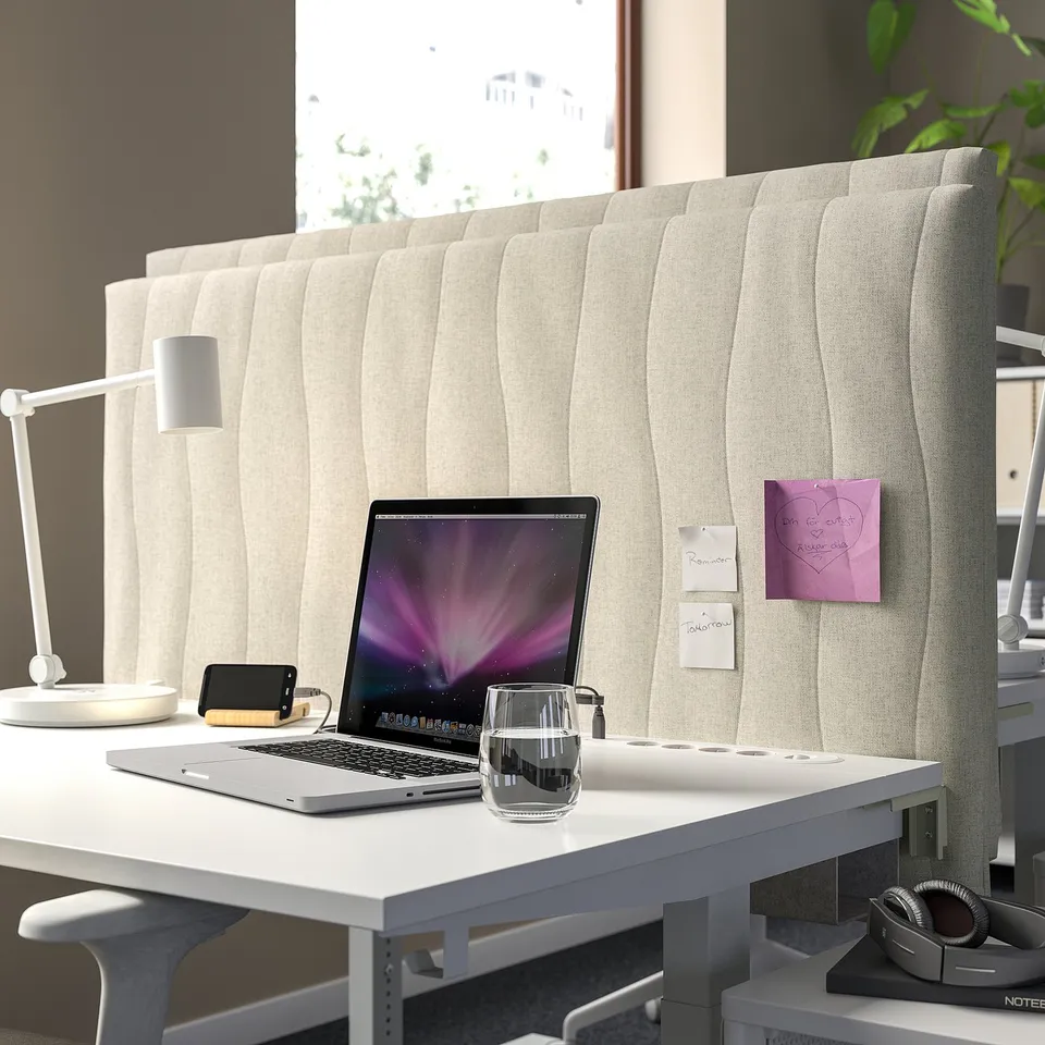 Modern office setup with MITTZON desk, laptop, lamp, and acoustic screen. Screen is beige, tall, with a rippled design, acting as a workspace divider.