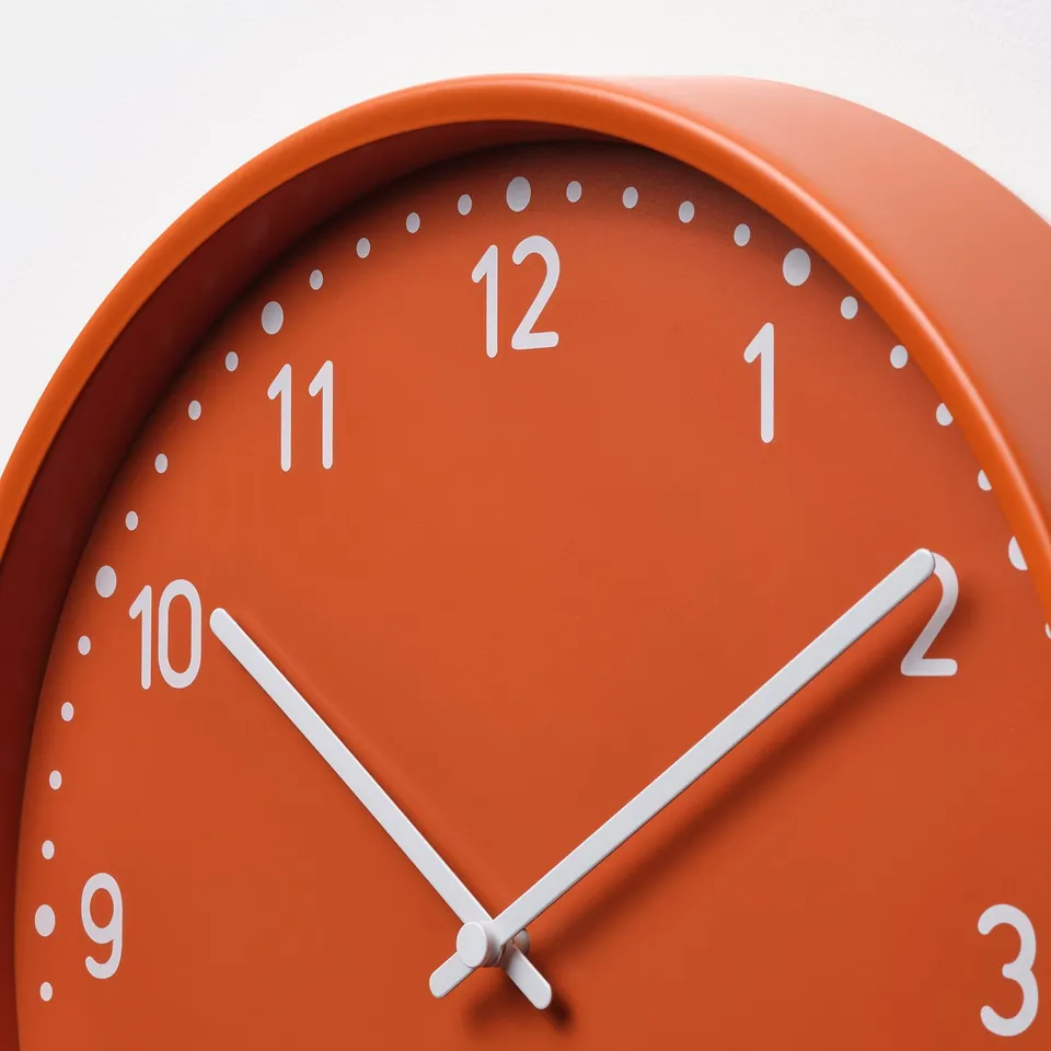 Bright orange clock with white silent hands, marked numbers, precise and stylish.