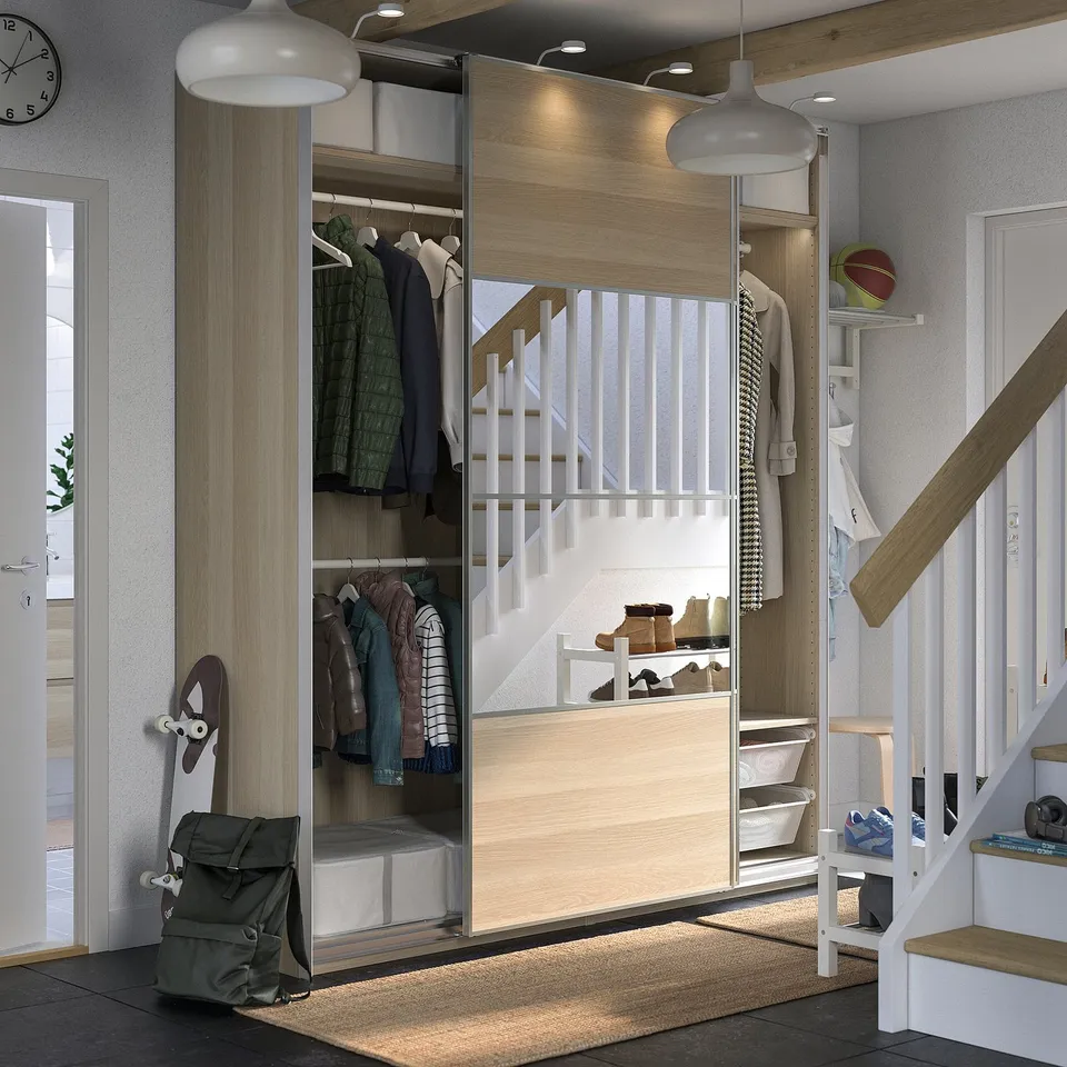 Modern entryway with sliding door wardrobe, clothes, and green backpack.
