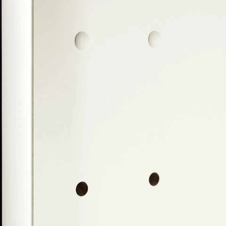 Four circular cover caps, two white, two black, intended to conceal unused drill holes in cabinetry or shelves, showcasing their functional design.