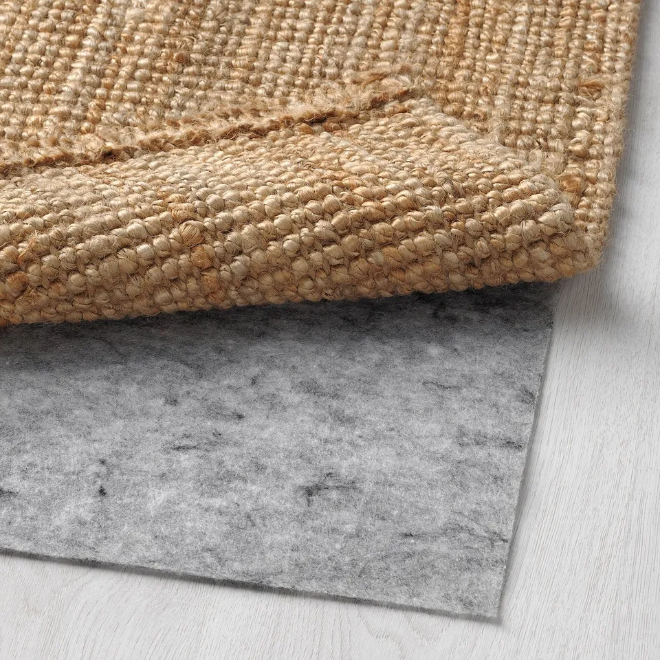 Close-up of natural jute rug on grey felt underlay.