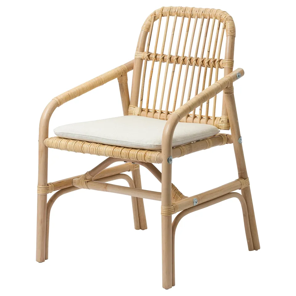 Displays a SALNÖ chair, a light beige, handwoven rattan piece with armrests and a cushioned seat, featuring a natural, curved design.