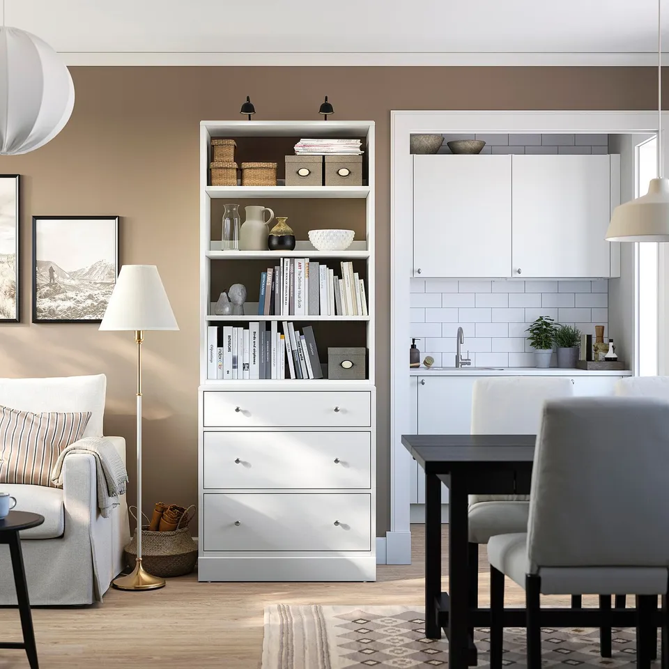 Stylish living room with HAVSTA chest, grey couch, black dining set, warm neutrals.