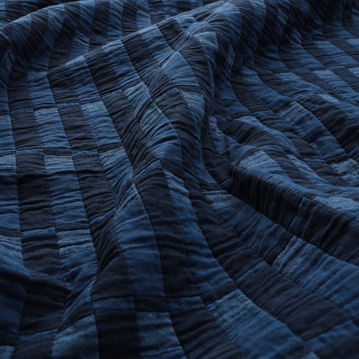 Dark blue quilted blanket with visible stitching, folded texture detail.