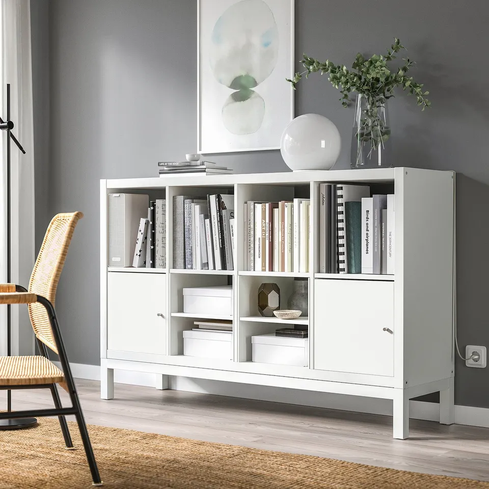 White KALLAX shelf with books, vase, and decor. Modern, closed storage. Smaller than grey wall version.