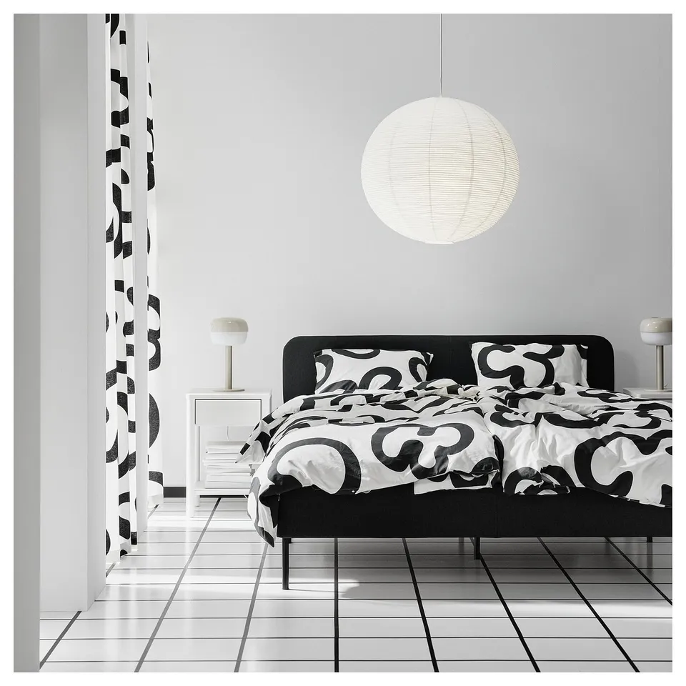GULLSUDARE lamp in white over black bed, casting soft light.