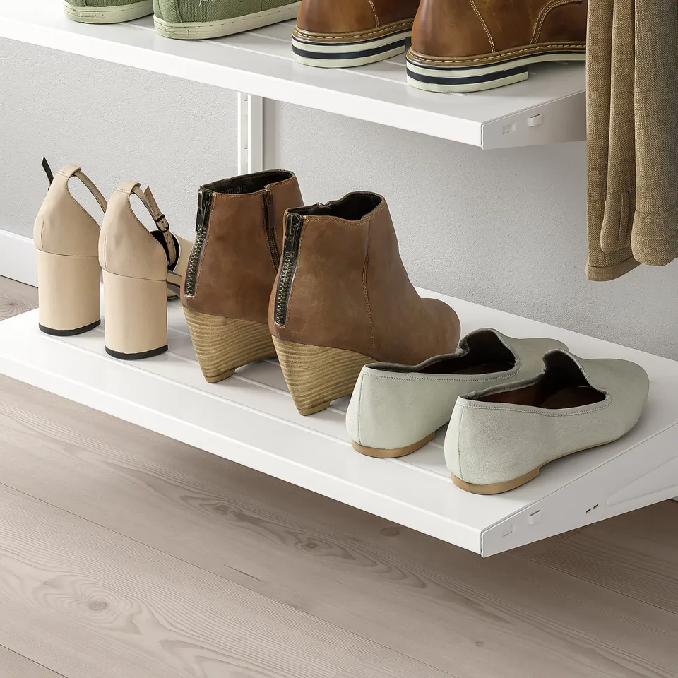 White wall-mounted shoe rack with various footwear neatly displayed on shelves.