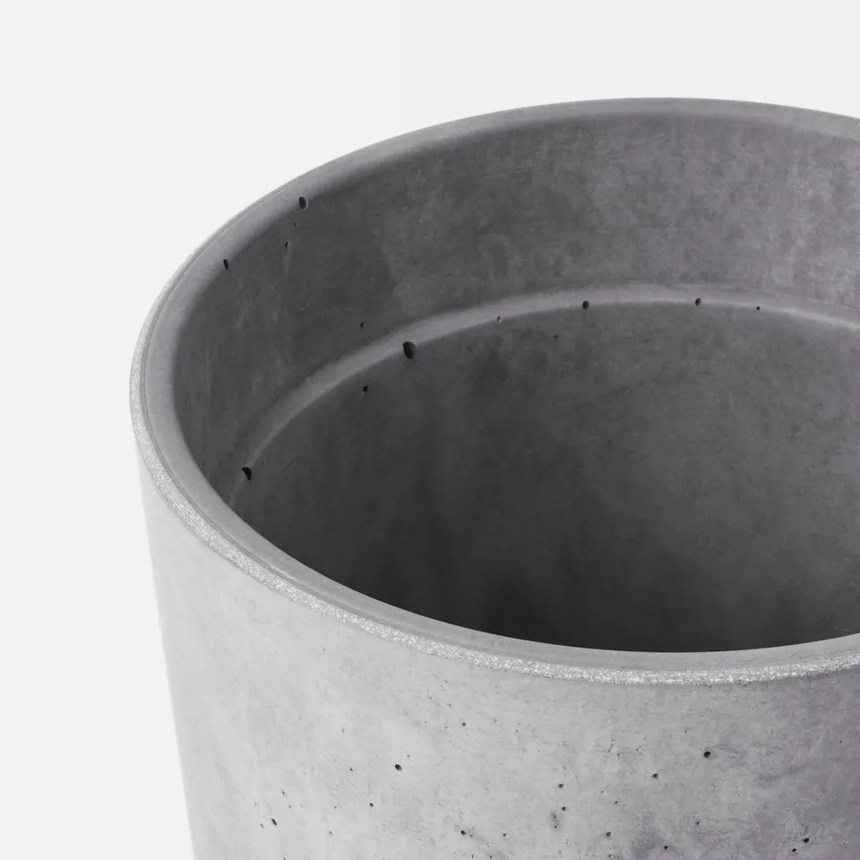 Cylindrical concrete planter with drainage holes, smooth surface, and soft feet.
