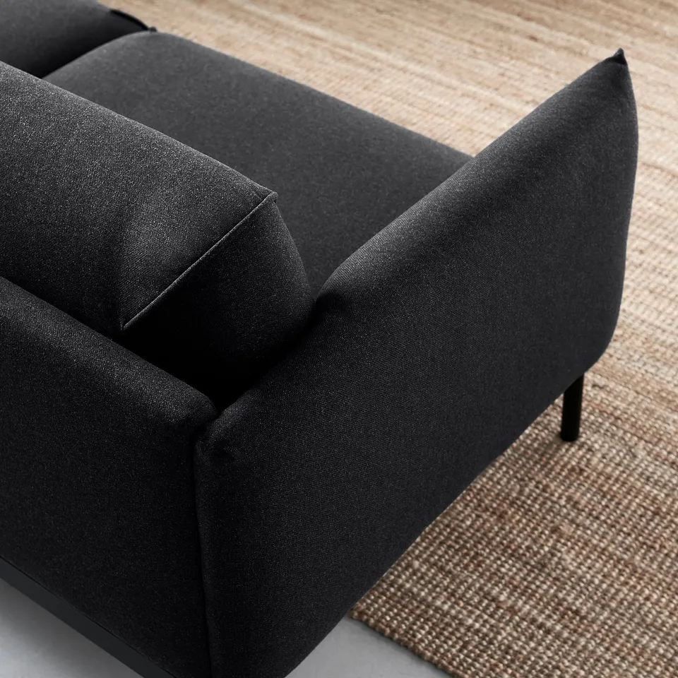 Modern black sofa with sleek lines and tapered legs on a woven rug.