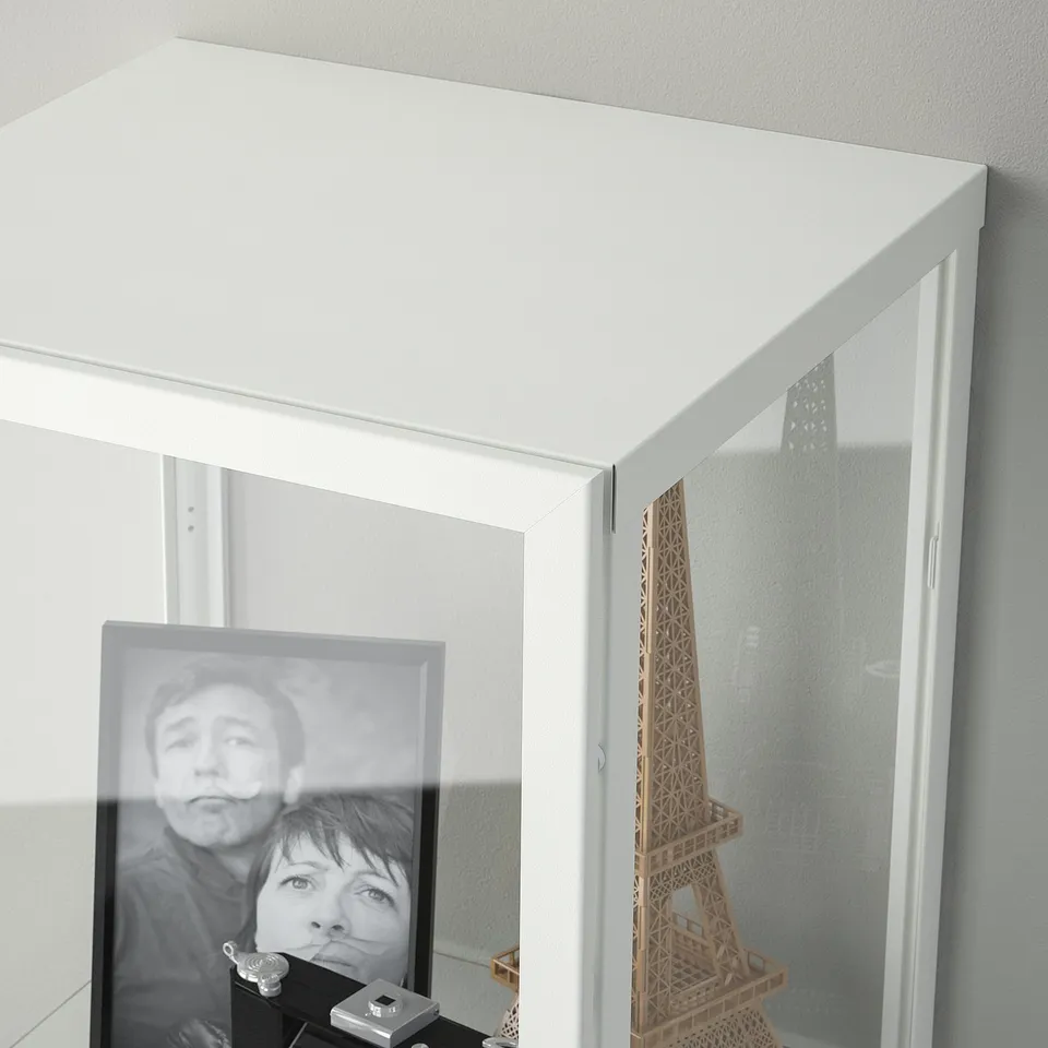 White glass-door cabinet displaying photo and eiffel tower model, with 3 adjustable shelves.
