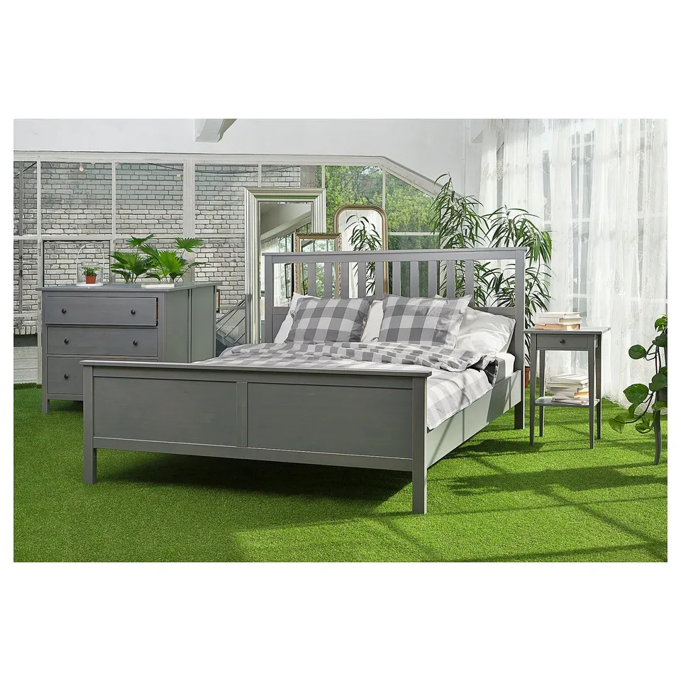 Bedroom scene with grey HEMNES bed, featuring slatted headboard, on green carpet.