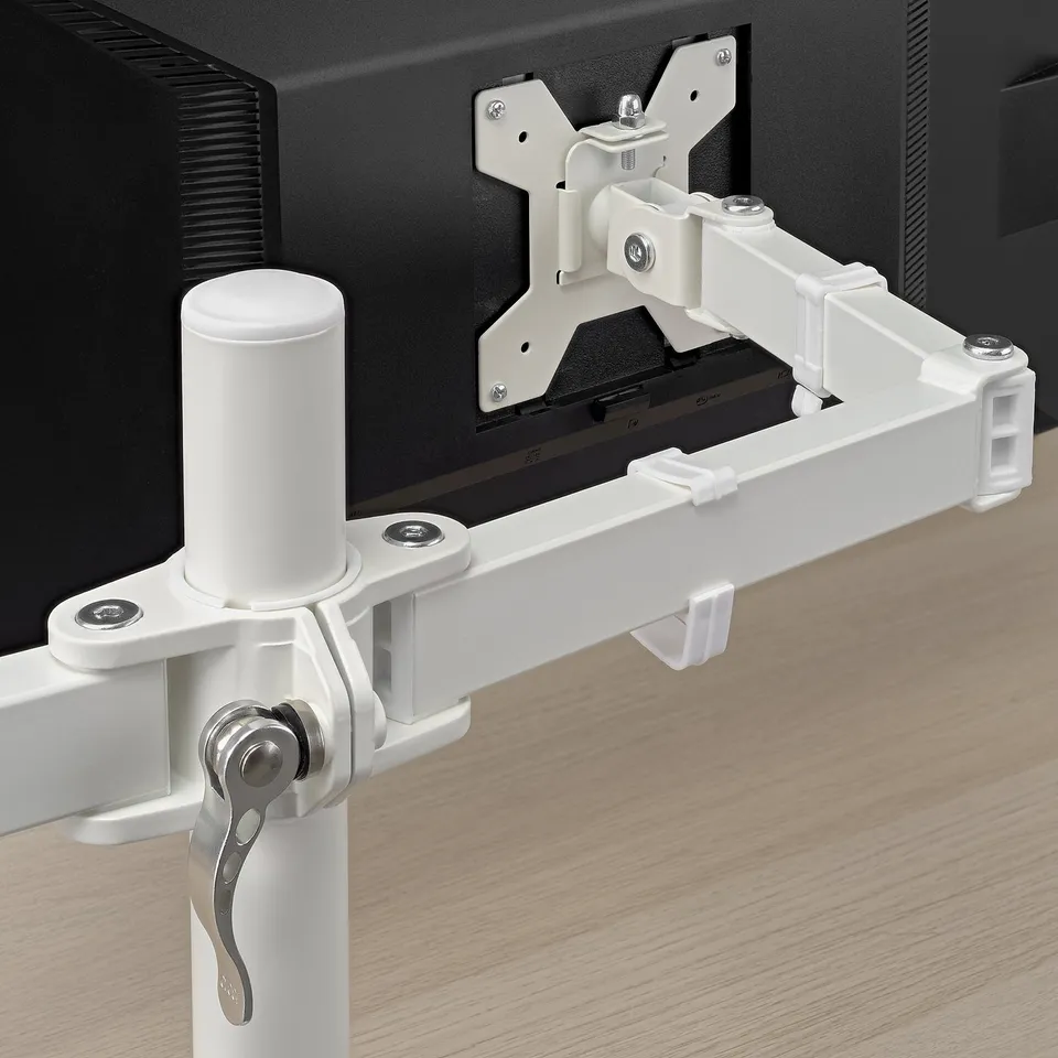 Close-up of a white monitor arm mounted on a desk, securely holding a monitor with adjustable brackets and clips.