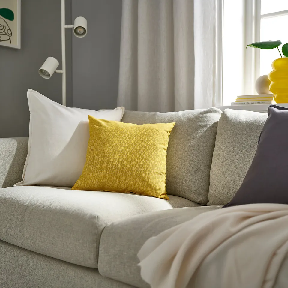 Living room with yellow PROFETBLOMMA pillows making a stylish statement on a neutral sofa.